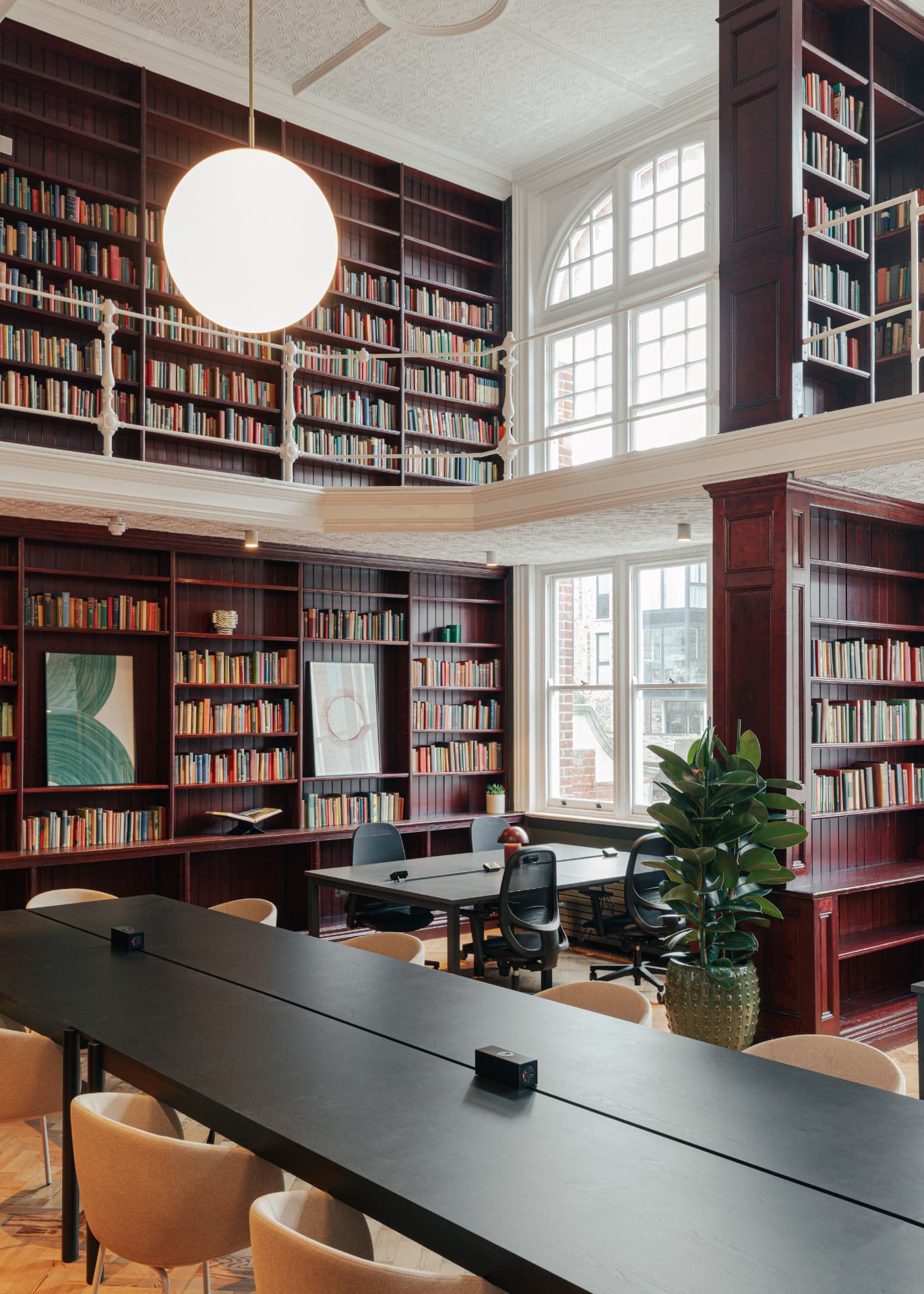 Double-height library workspace with long meeting tables