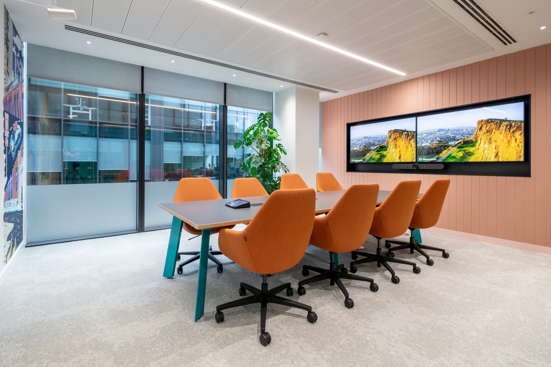 Meeting room with orange chairs and video conferencing screens fitted out by Hunters